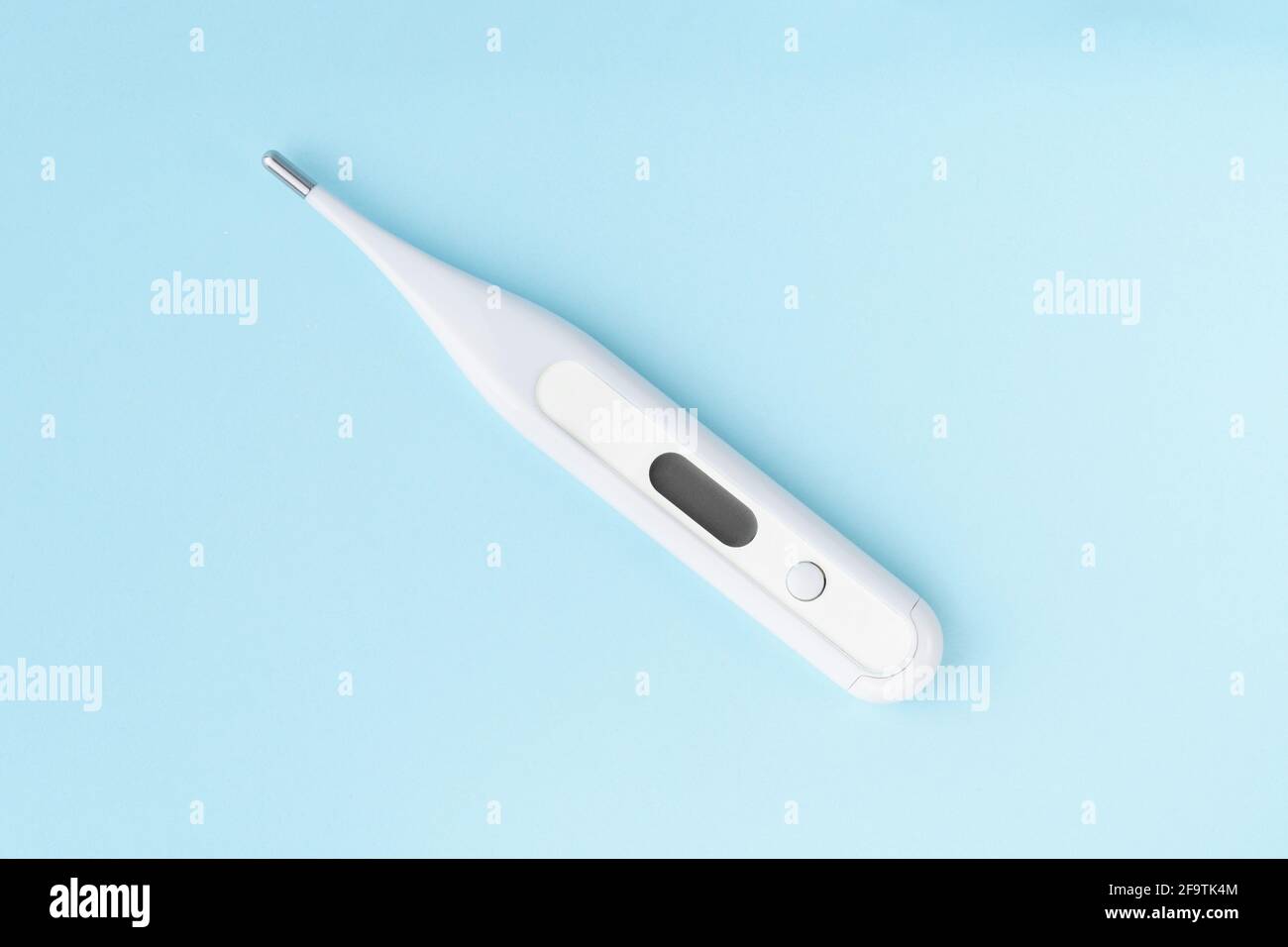 Termometro elettronico per il corpo su sfondo blu. Moderno termometro con display digitale, strumento diagnostico Foto Stock