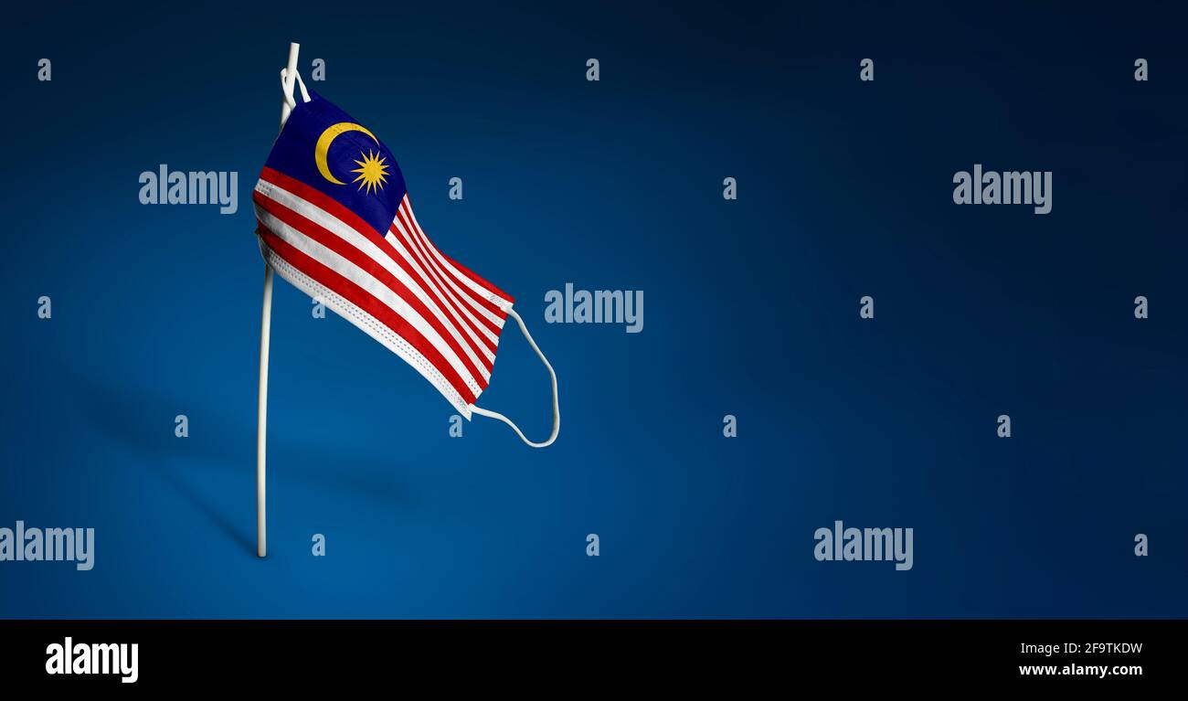 Maschera Malesia su sfondo blu scuro. Bandiera ondulata della Malesia dipinta su maschera medica sul palo. Flag di attacco del virus. Concetto della bandiera della lotta Foto Stock