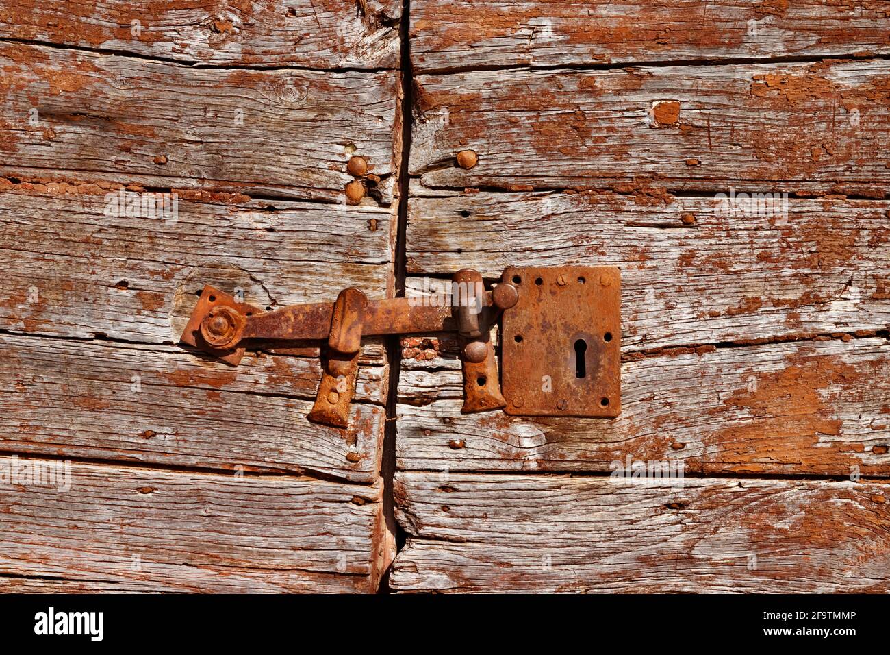 Vecchio ferro arrugginito vintage chiusura sulla porta incrinata, la porta è fatto di tavole orizzontali di legno verniciate marrone Foto Stock