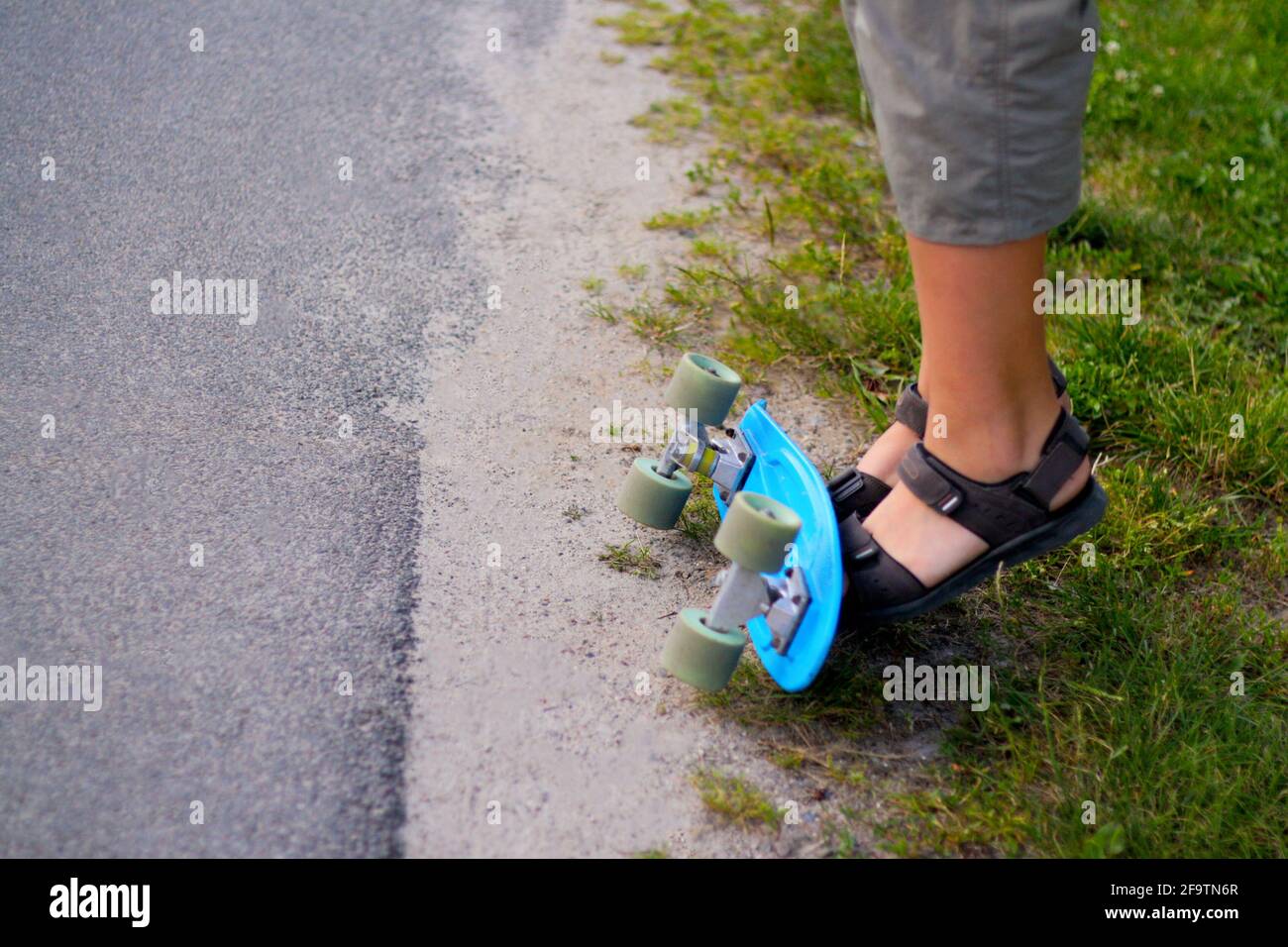 Sfida il ragazzino facendo trucchi su uno skateboard penny. Bambini in giro nel parco a bordo di uno skateboard. Il bambino impara a cavalcare un bordo blu del penny e a fare Foto Stock