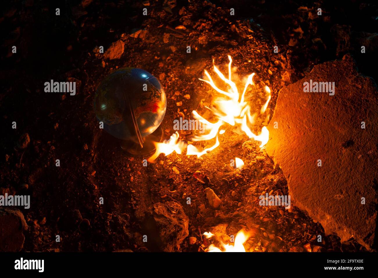 Globe rimanere sul pavimento roccioso vicino al fuoco fiammeggiante Foto Stock