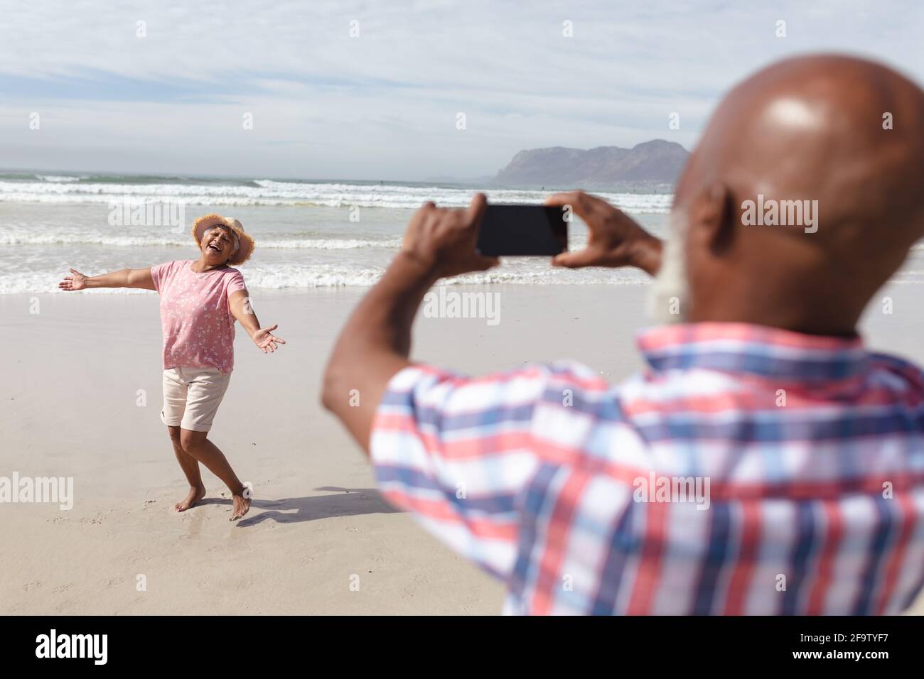 Uomo afro-americano anziano scattando una foto di sua moglie sulla spiaggia Foto Stock