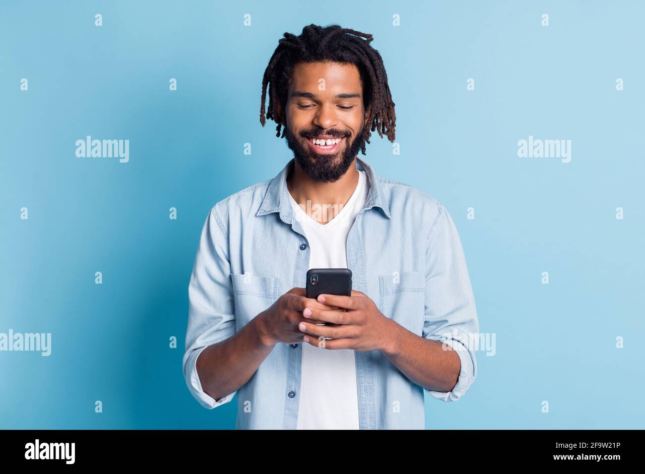 Ritratto di attraente ragazzo focalizzato allegro utilizzando il dispositivo chatting gratuito tempo isolato su sfondo di colore blu brillante Foto Stock