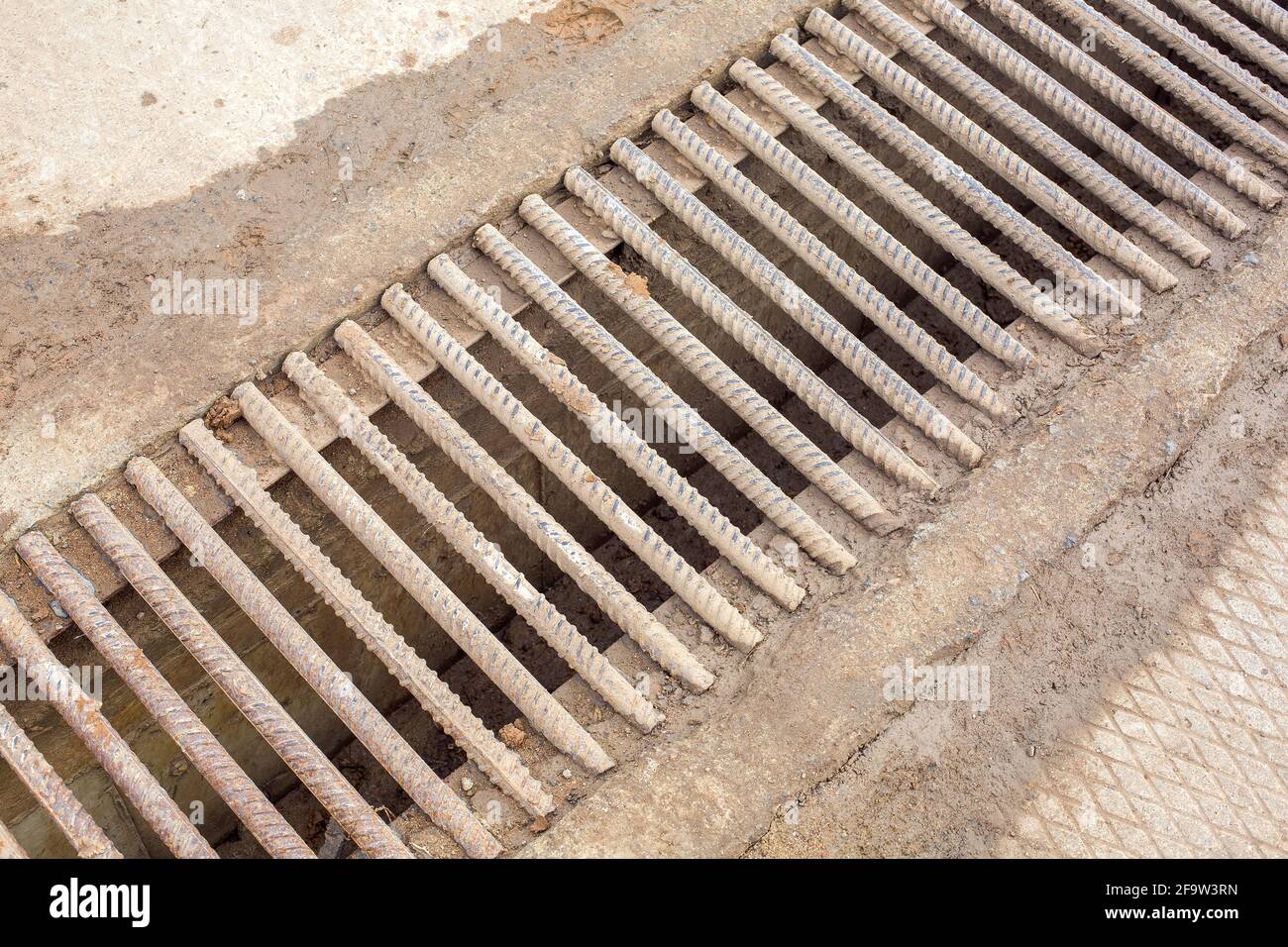 canale di drenaggio con una griglia di raccordi in ferro tondini sporchi in  argilla, sistema di infrastrutture per acque reflue industriali primo piano  Foto stock - Alamy