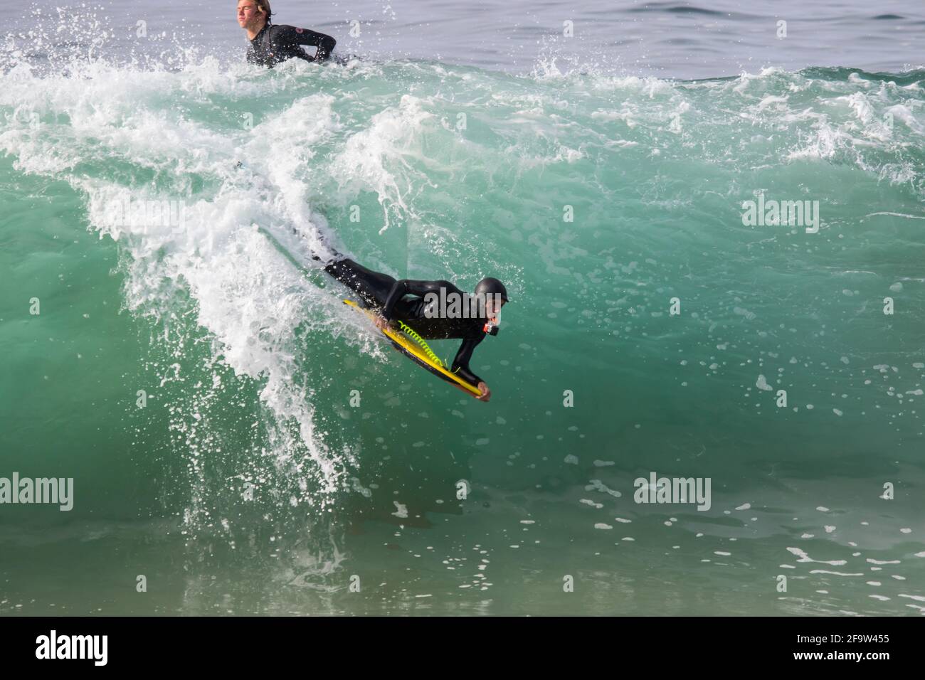 Bodyboarder che cavalca un'onda e filma con una fotocamera impermeabile in bocca Foto Stock