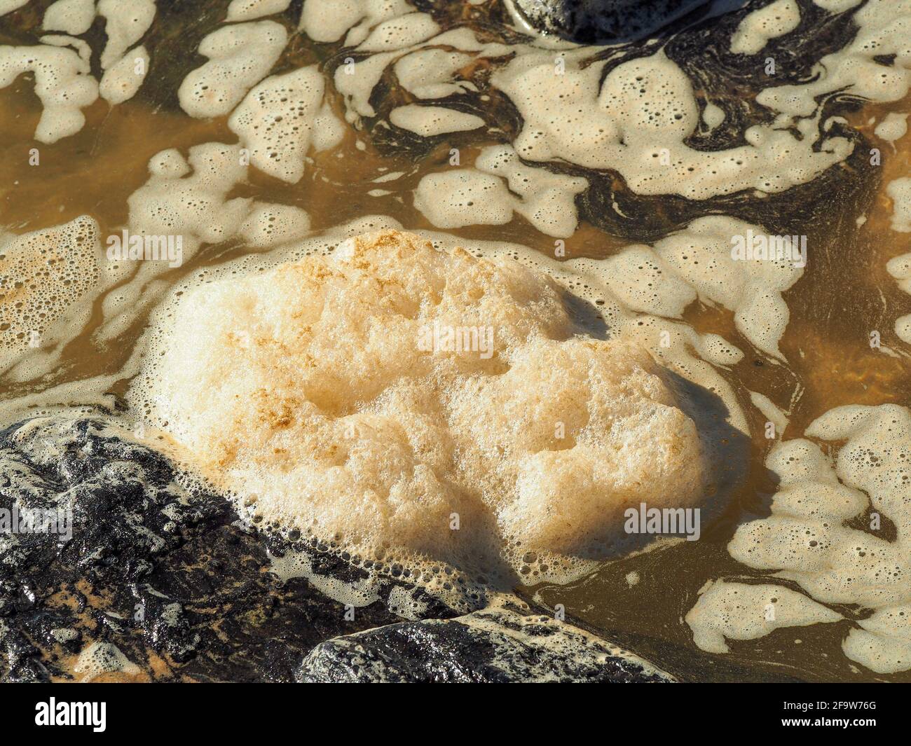 Acqua di mare schiumosa e spumeggiante nelle piscine di roccia Foto Stock