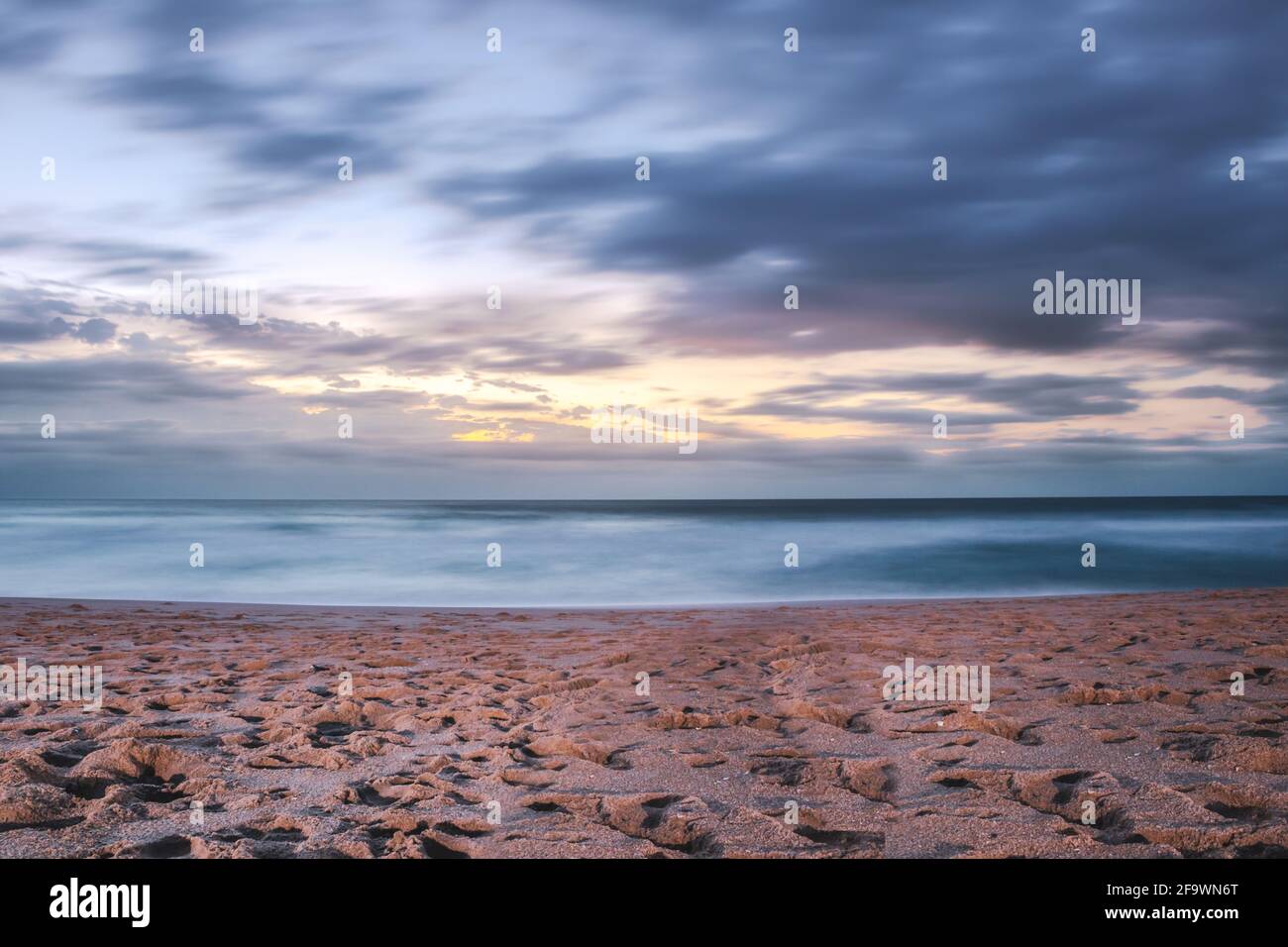 Un'alba nuvolosa sovrastata su un oceano Indiano da un punto di vista su una spiaggia a Port Shepstone, Kwa-Zulu Natal, Sudafrica Foto Stock