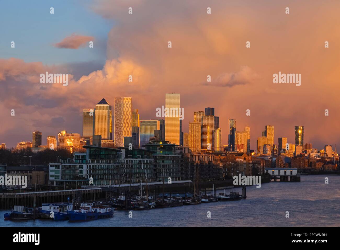 Inghilterra, Londra, Docklands, Fiume Tamigi e Canary Wharf Skyline con luce del tardo pomeriggio sulle nuvole di tempesta Foto Stock