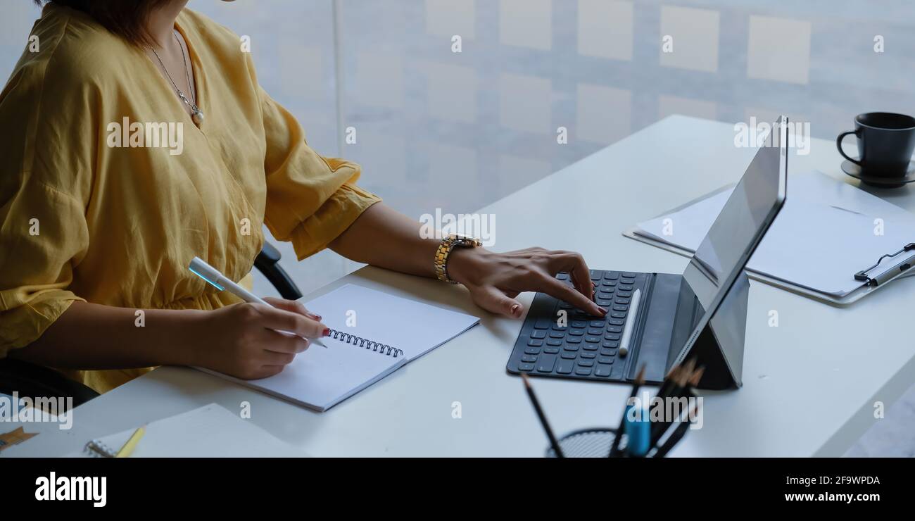 Asian Business Woman che lavora con tablet in ufficio. Concetto di lavoro da casa. Foto Stock