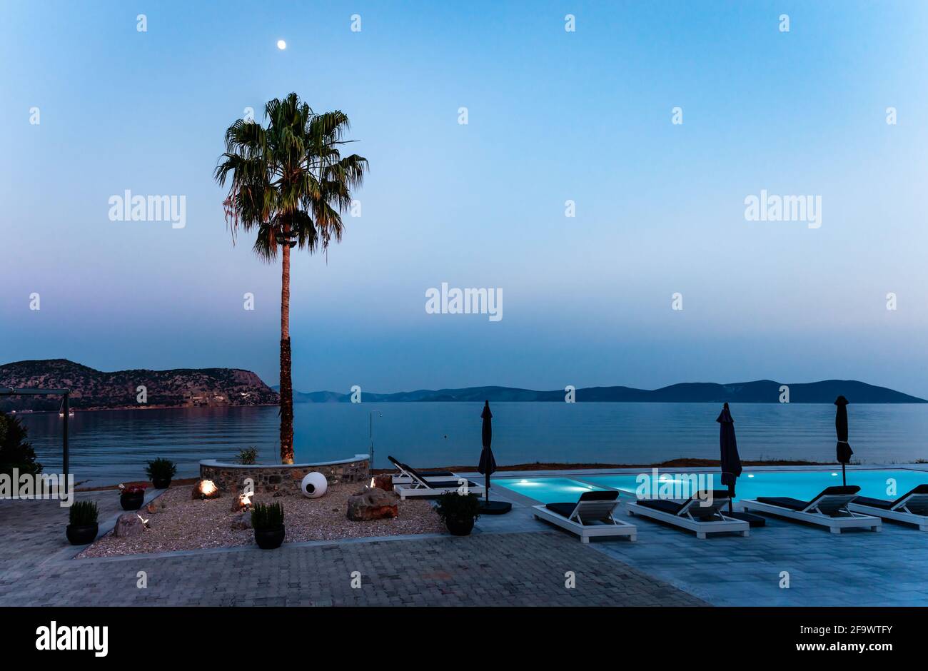 Una piscina sul mare di notte. Luna su un albero di palma. Foto scattata a Ermioni, Peloponneso, Grecia. Foto Stock
