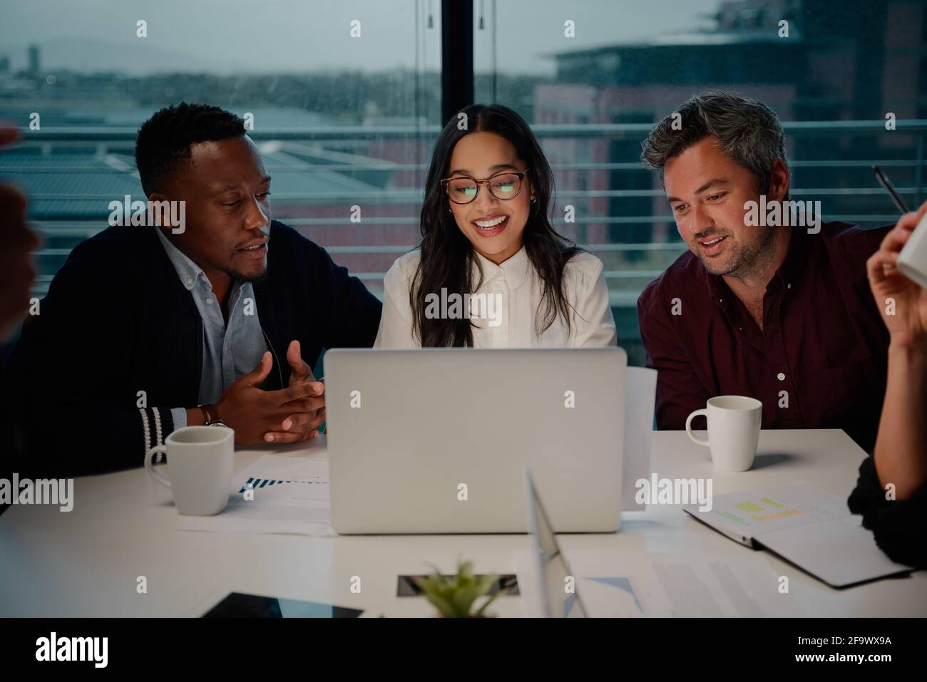 Gruppo di colleghi diversi di successo che guardano al laptop in riunione Foto Stock