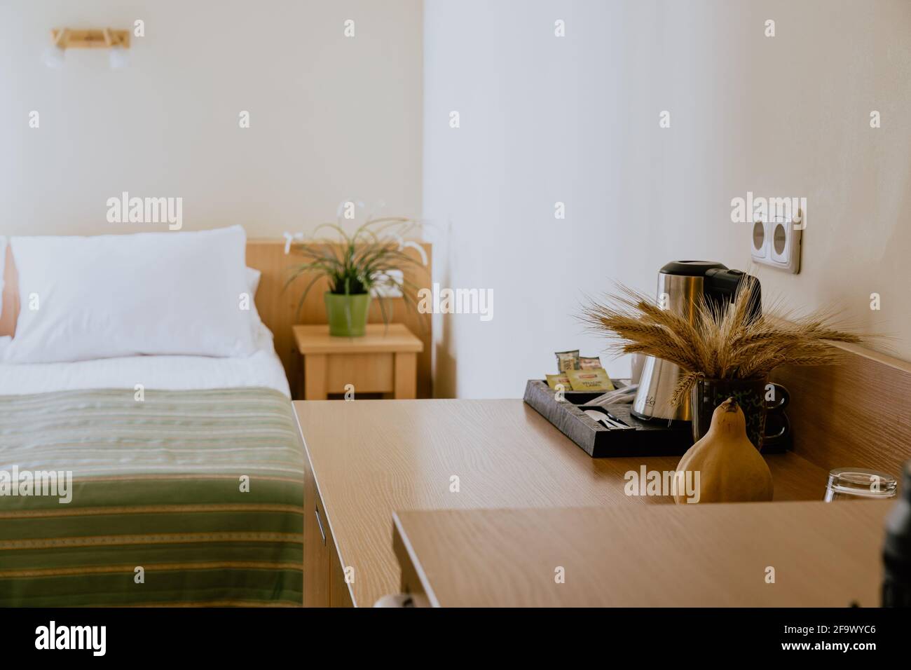 Interno di una camera d'hotel semplice e ben arredata con un letto singolo durante il giorno Foto Stock