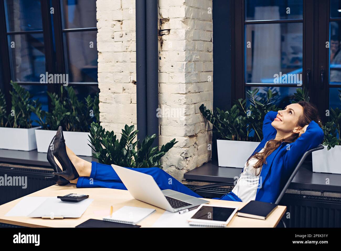 donna d'affari che si rilassa sulla sedia in ufficio Foto Stock