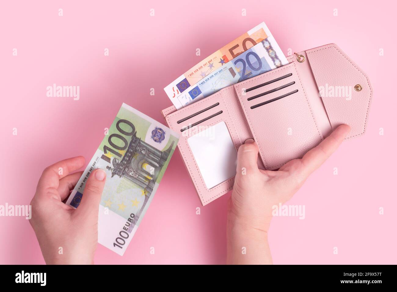 Mani che tengono il portafoglio, contando contanti o pagando. Portafoglio in pelle rosa con euro in mani femminili. Le mani della donna che prendono le banconote europee fuori dal pu Foto Stock