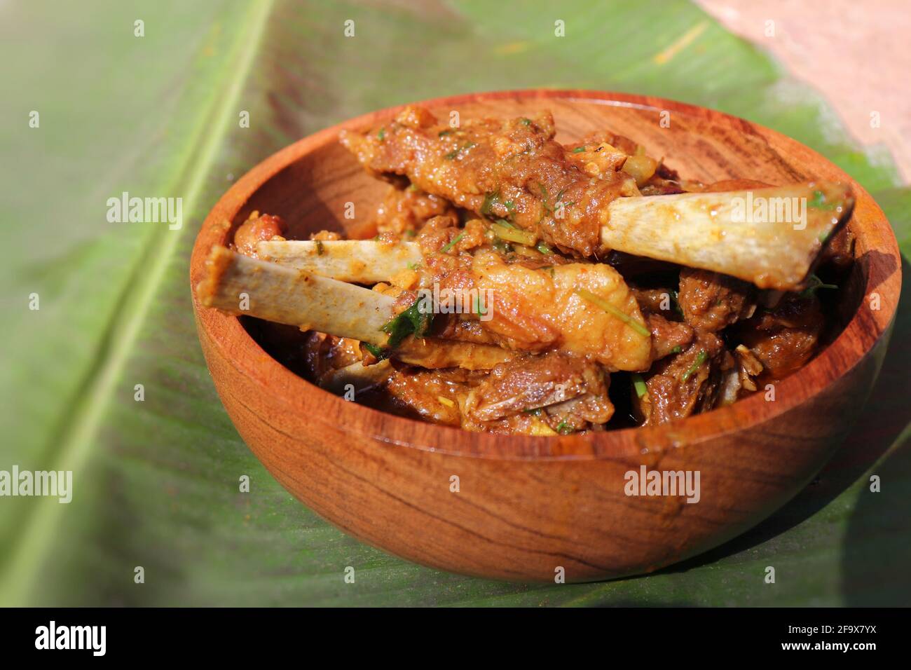 Mutton trita il curry. Curry di capra rustico indiano piccante non vegetariano. Servito in una ciotola di legno su uno sfondo di foglia di Banana. Spazio di copia. Foto Stock