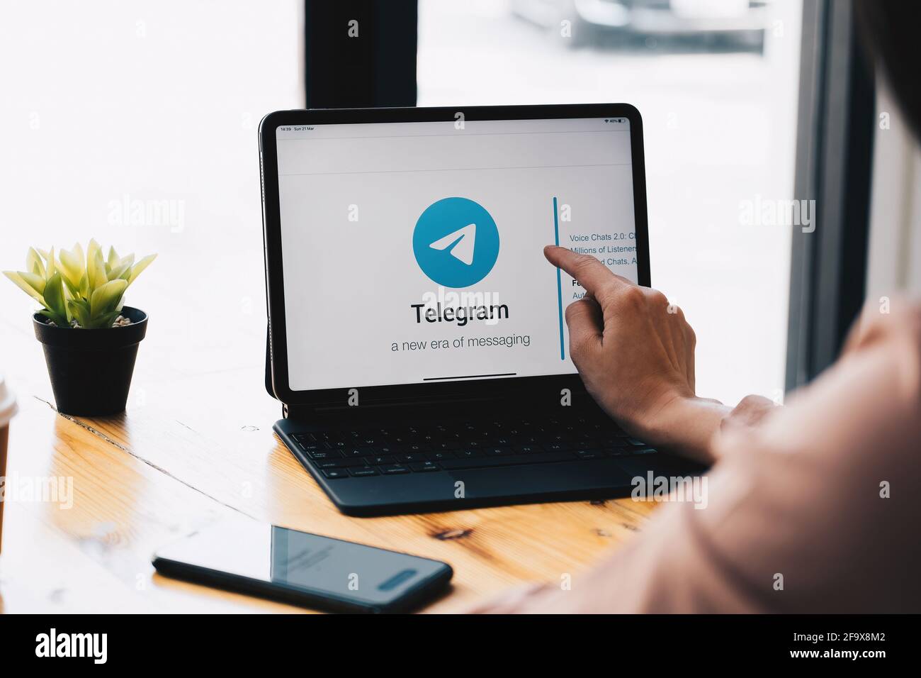 CHIANG mai, THAILANDIA, 21 MARZO 2021 : Donna mano utilizzando iPad Pro con servizio di social networking telegram sullo schermo. IPhone 10 è stato creato e. Foto Stock