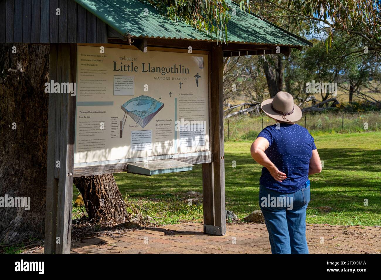 Persona che legge informazioni bordo all'entrata alla riserva naturale di Little Llangothlin, NSW, Australia Foto Stock