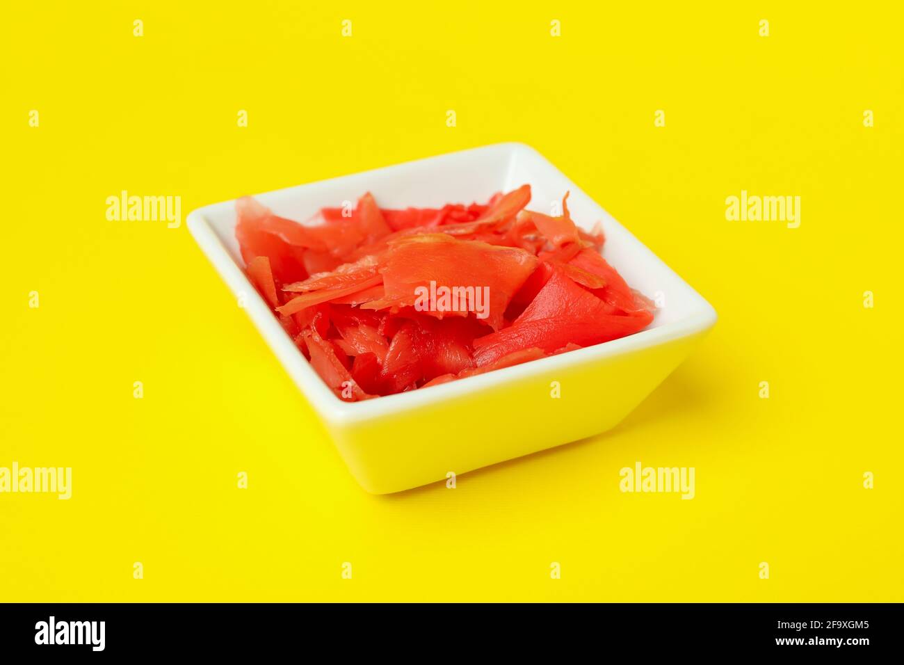 Ciotola con zenzero rosso su sfondo giallo Foto Stock