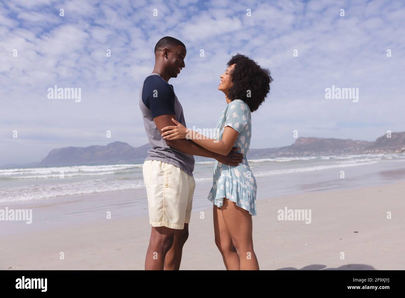 Coppia afro-americana in piedi e guardarsi a vicenda la spiaggia sorridente Foto Stock