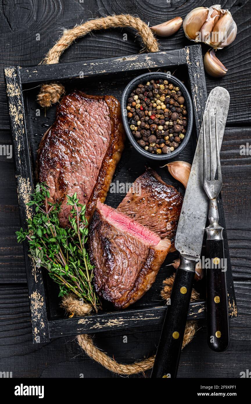 Barbecue cappello groppa grigliato o bistecca brasiliana di carne di manzo  picanha in un vassoio di legno sfondo di legno nero. Vista dall'alto Foto  stock - Alamy