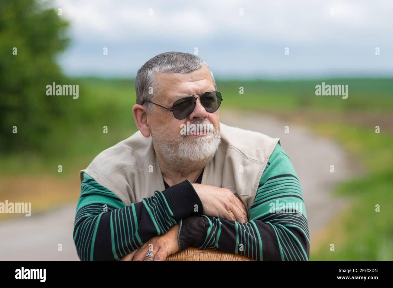 Bel ritratto esterno di uomo caucasico in nero occhiali da sole appoggiati su una sedia in vimini Foto Stock