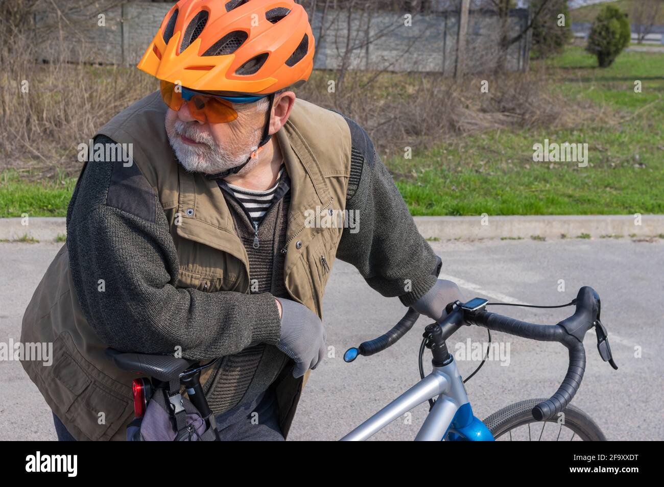 Bel ritratto all'aperto di un anziano caucasico bearded che guarda quando si è pronti a cavalcare su una bicicletta in ghiaia Foto Stock