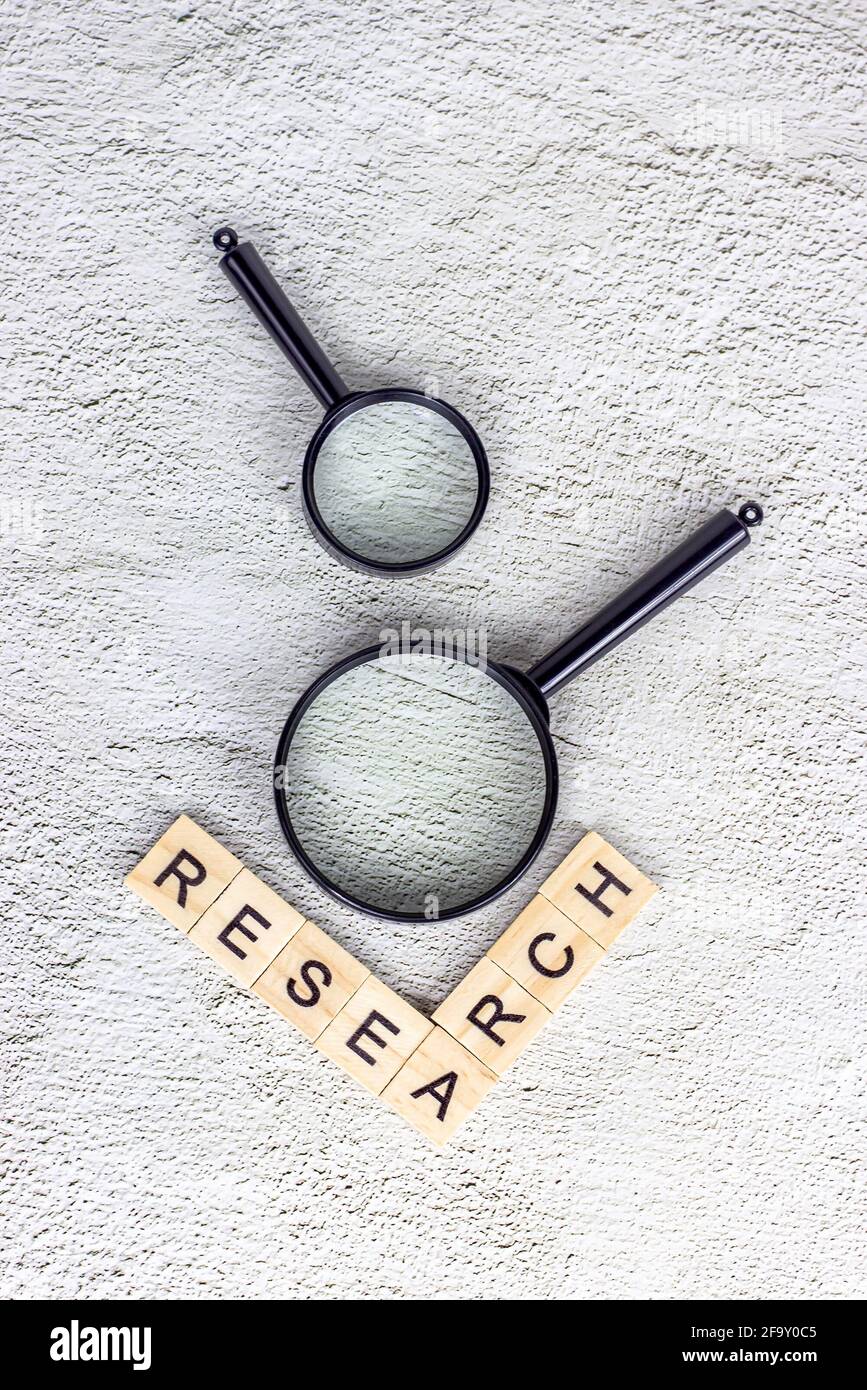 Lente d'ingrandimento nera con testo di ricerca su sfondo grigio chiaro. Analisi statistica e ricerca scientifica. Foto Stock