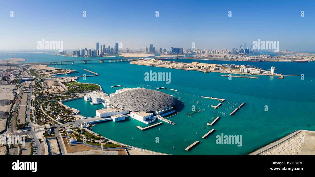 Abu Dhabi, Emirati Arabi Uniti - 6 aprile 2021: Museo del Louvre e paesaggio urbano aereo di Abu Dhabi che si innalzano dalle acque marine dell'Emirati Arabi Uniti Foto Stock