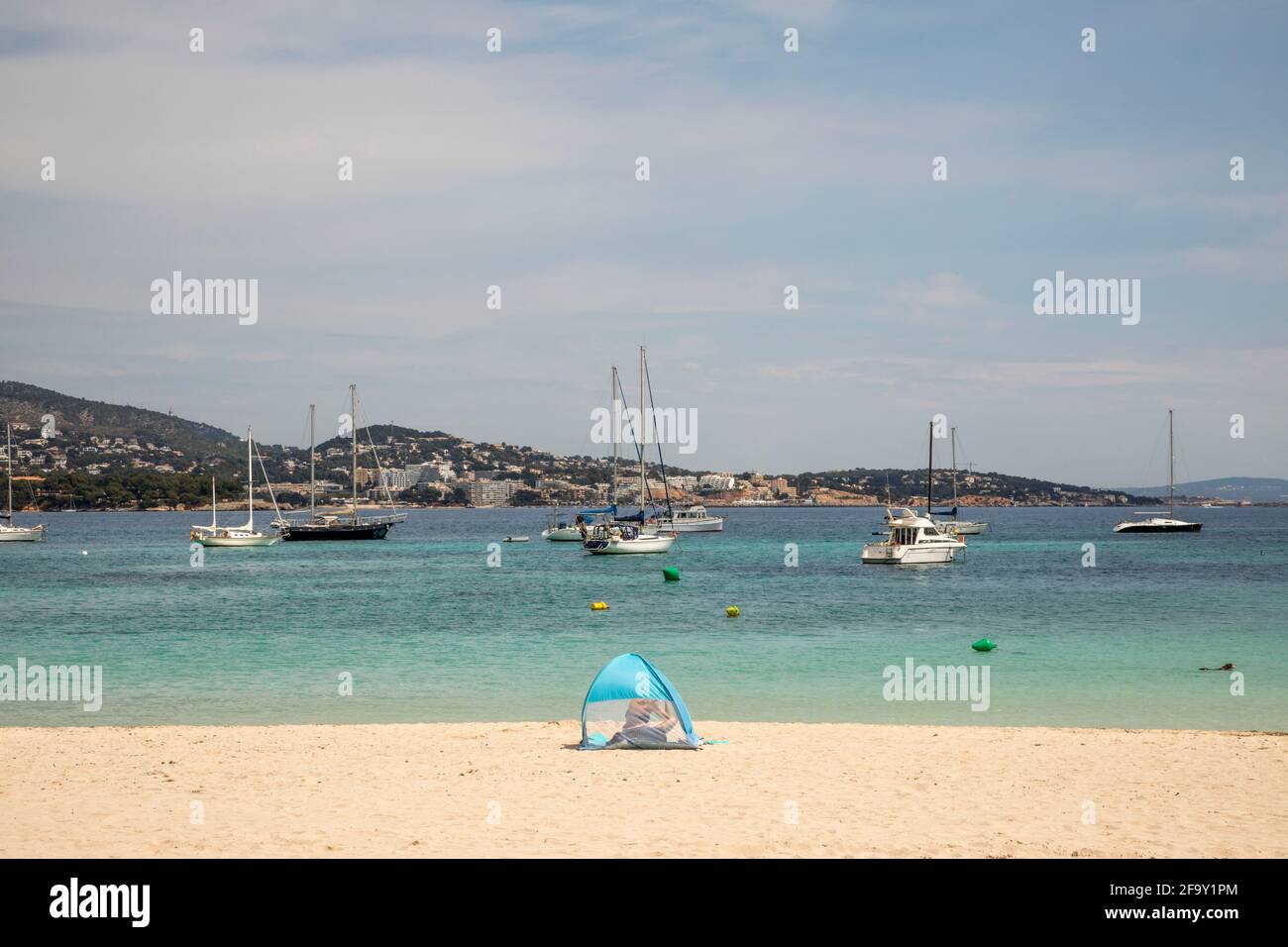 Palmanova, Maiorca, Spagna. 20 Apr 2021. Vista sulla spiaggia di una donna e una tenda a vento di fronte al mare e barche a Pamanova a Maiorca. Credit: John-Patrick Morarescu/ZUMA Wire/Alamy Live News Foto Stock