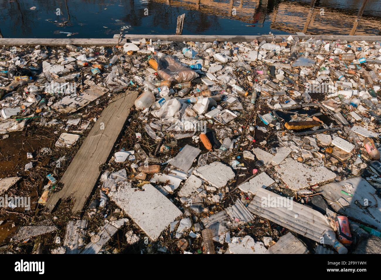 Rifiuti e rifiuti si raccolgono nel fiume urbano causando un ritorno di inquinamento. Foto Stock