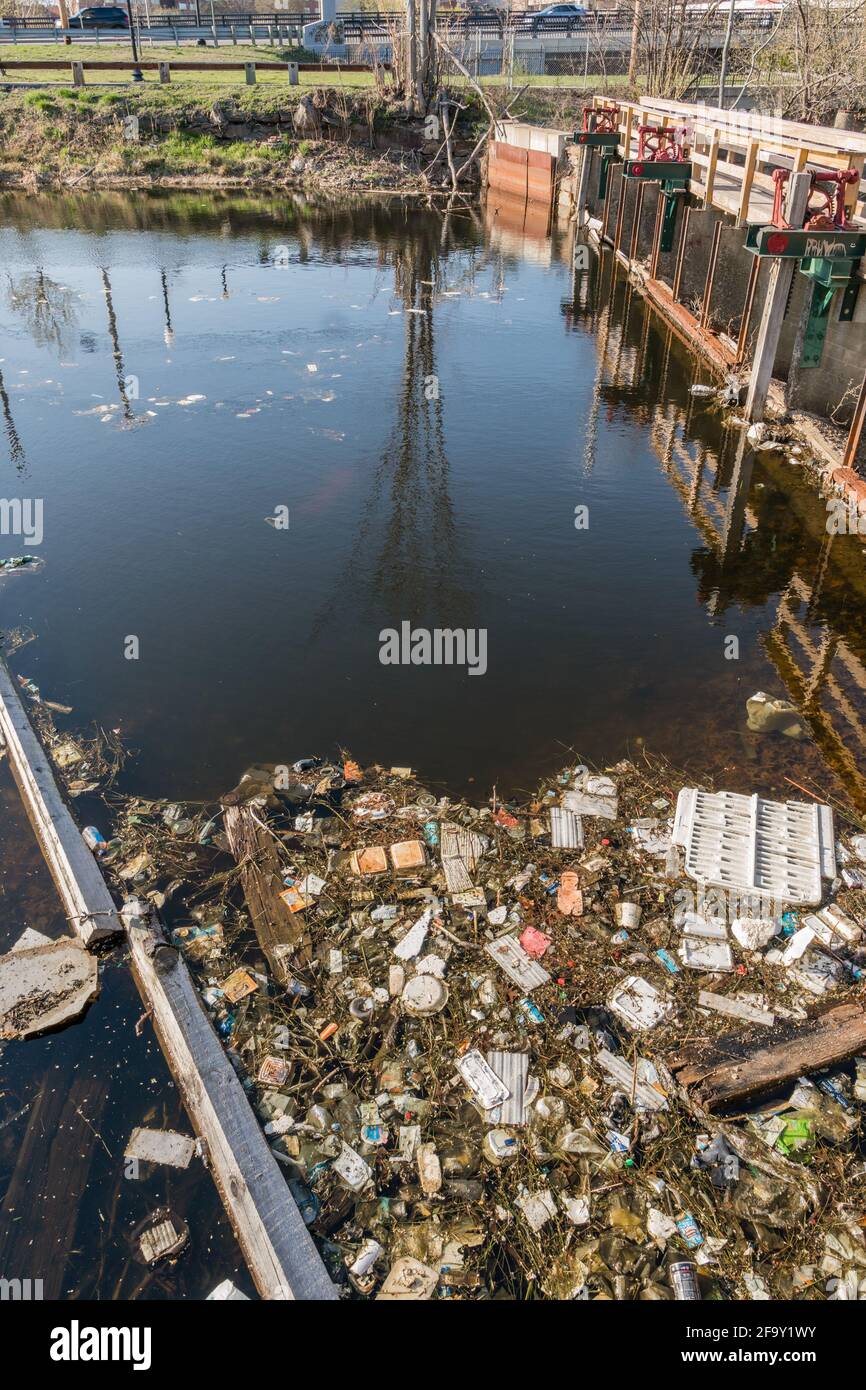 Rifiuti e rifiuti si raccolgono nel fiume urbano causando un ritorno di inquinamento. Foto Stock