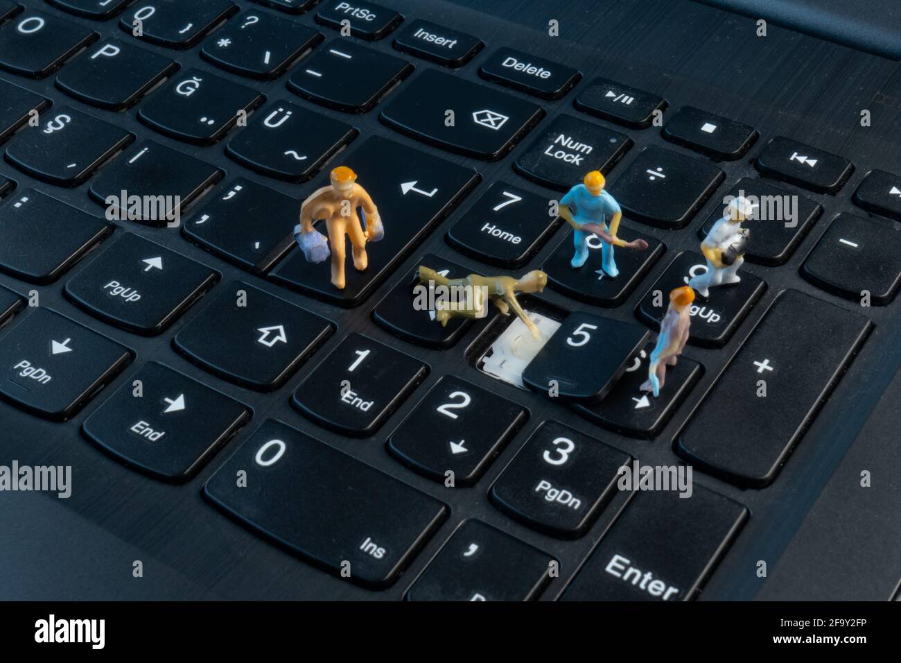 I mini lavoratori che lavorano sul pulsante sulla parte superiore della tastiera Foto Stock