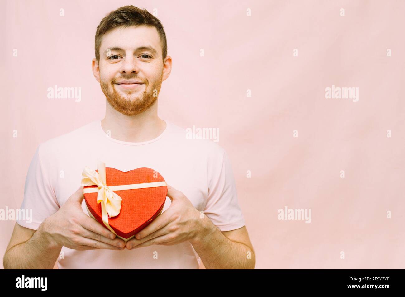 l'uomo tiene in mano una scatola regalo a forma di cuore. Concetto di giorno di San Valentino Foto Stock