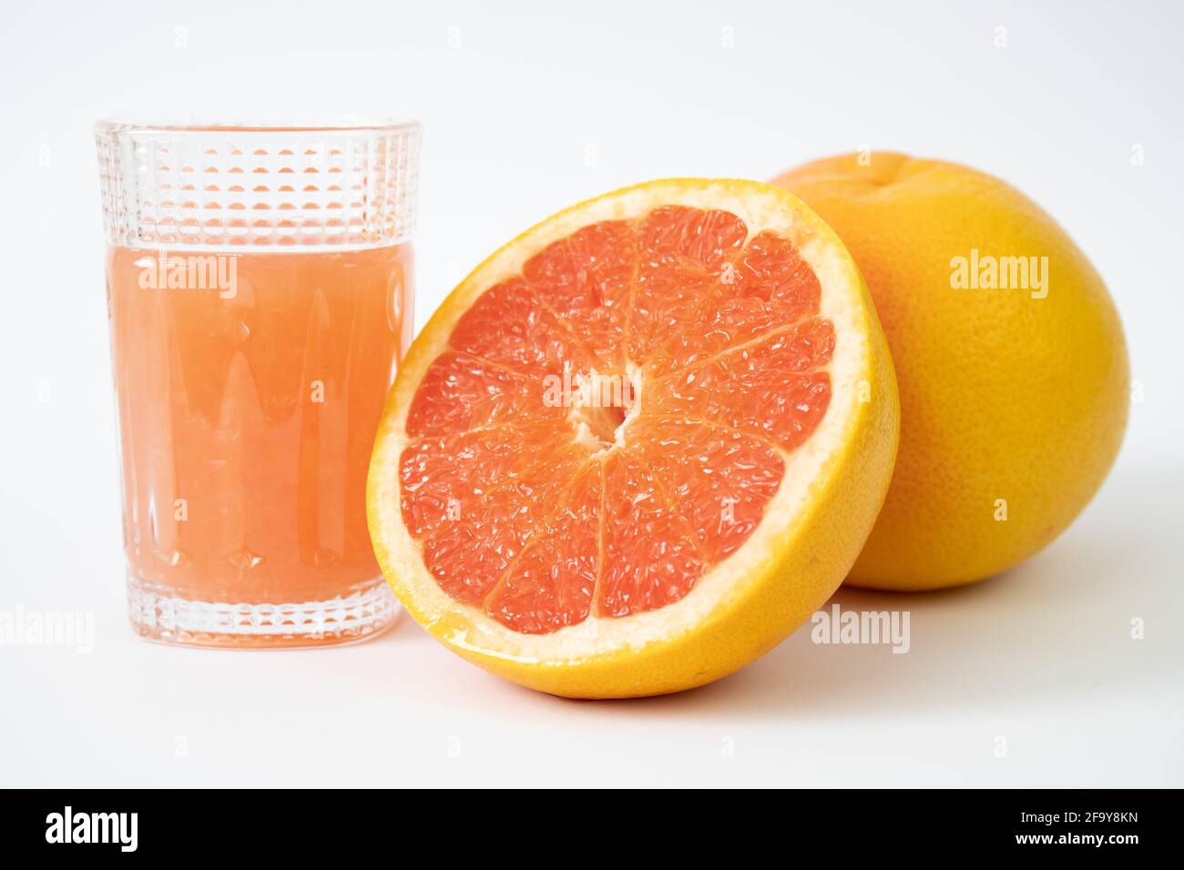 Una metà di pompelmo, un pompelmo intero e un bicchiere di succo di pompelmo. Foto Stock