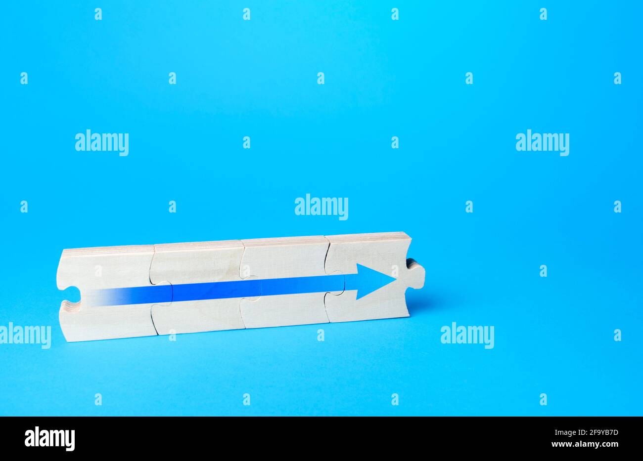 Puzzle assemblato con una freccia blu. Proseguimento del processo, ulteriori progressi. Andare avanti, direzione dello sviluppo. Concetto di crescita della carriera, promo Foto Stock