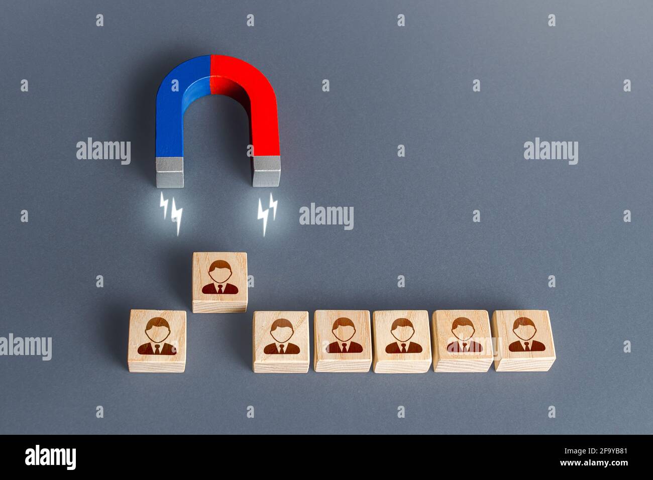 Il magnete tira una persona fuori dai blocchi di fila. Scelta del candidato migliore per l'assunzione. Brocciando i partecipanti di un altro team aziendale. Concetto di luring. Concorso Foto Stock