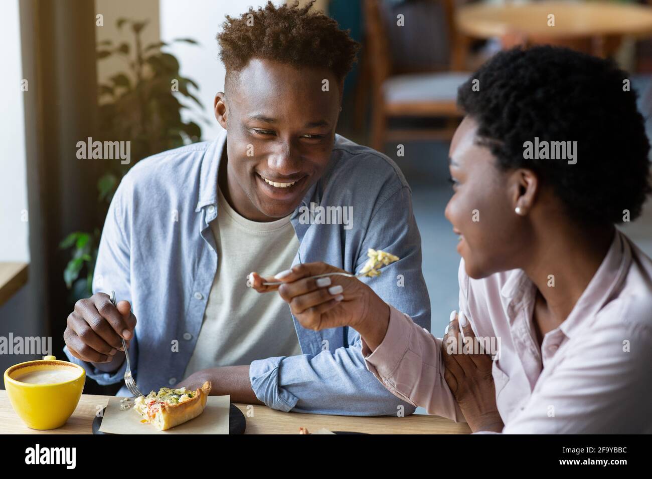 Cena romantica di San Valentino. Una coppia nera che ama mangiare insieme la torta al caffè, trascorrendo momenti accoglienti con ogni oher Foto Stock