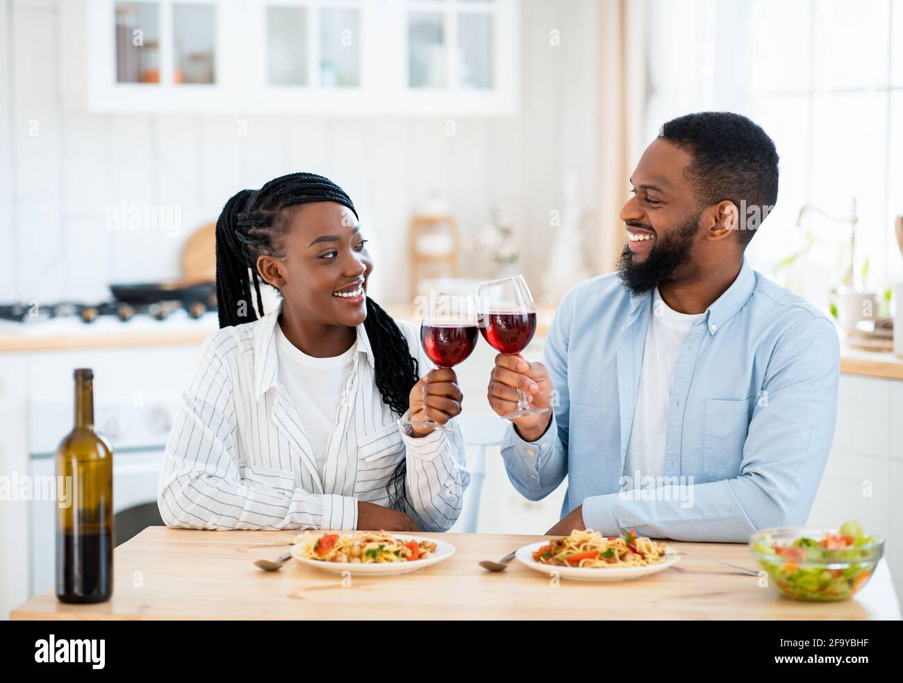 Date di quarantena. Happy Black Couple bevendo vino e pranzando a casa Foto Stock