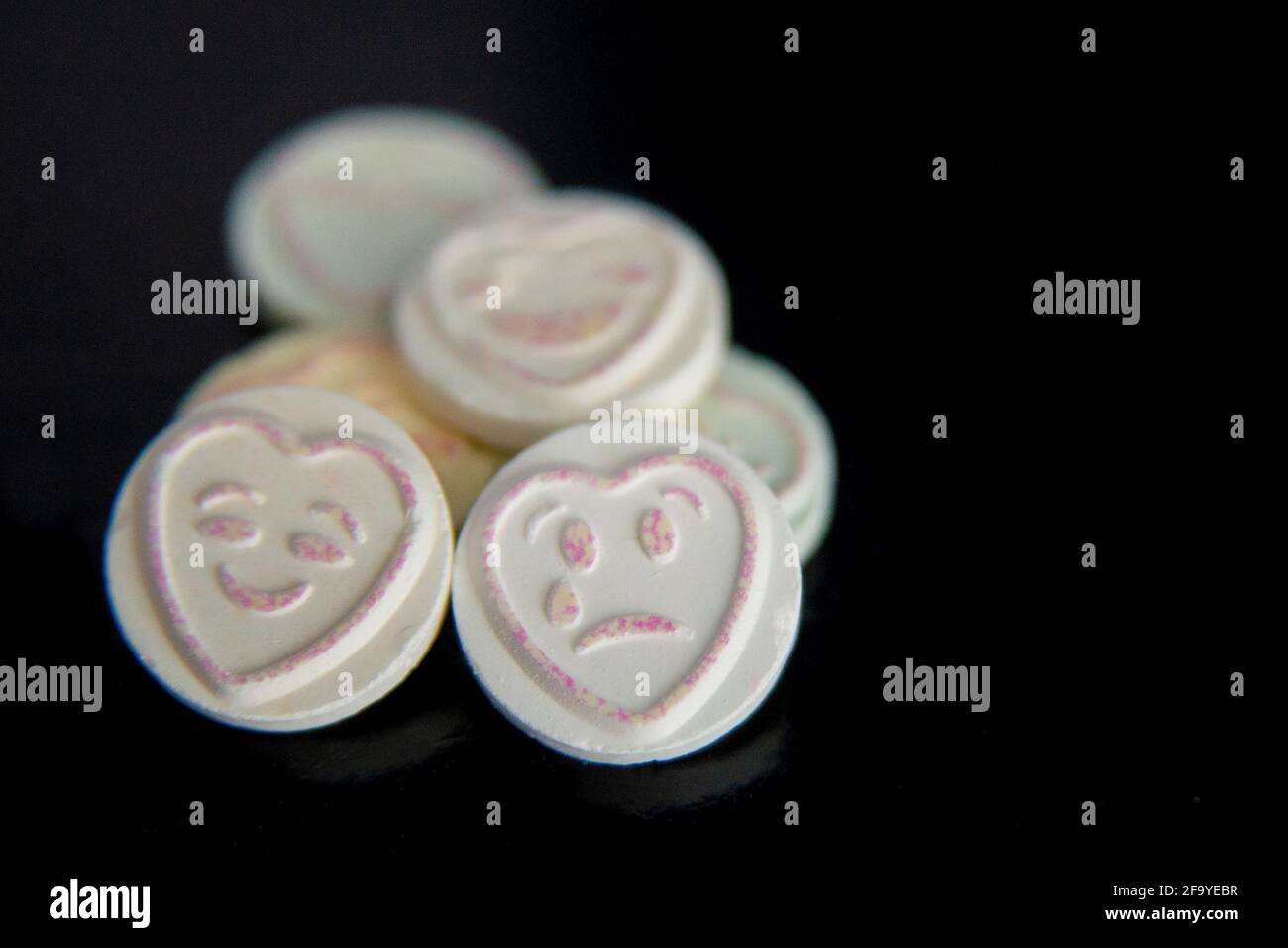 Amore cuore emoticon dolce emojis su sfondo nero, volto triste e volto felice. Mettere a fuoco sul volto triste. Salute mentale, depressione, consapevolezza della salute mentale Foto Stock