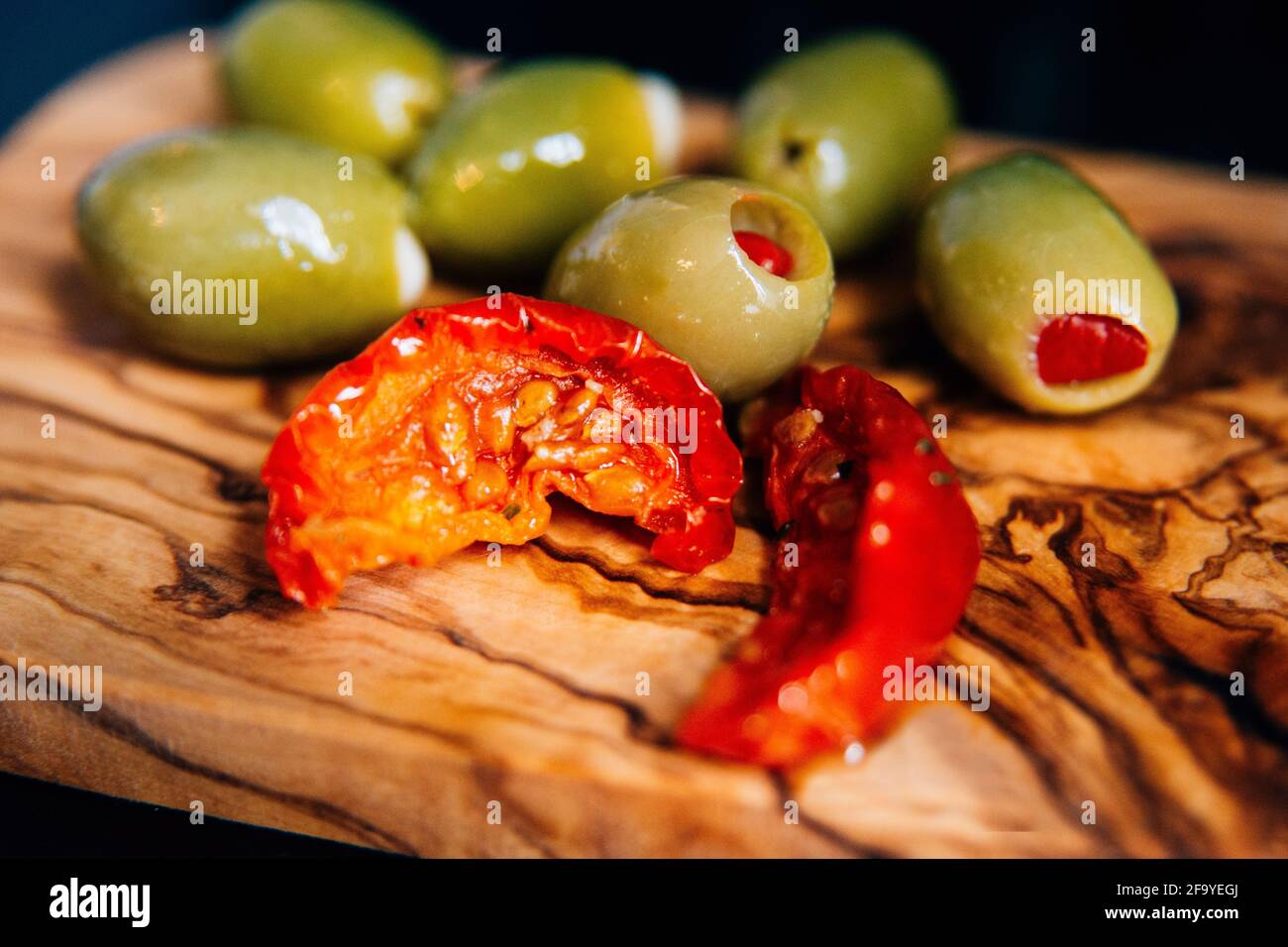 primo piano di una tagliere di legno di bambù con il sole pomodori secchi e olive Foto Stock