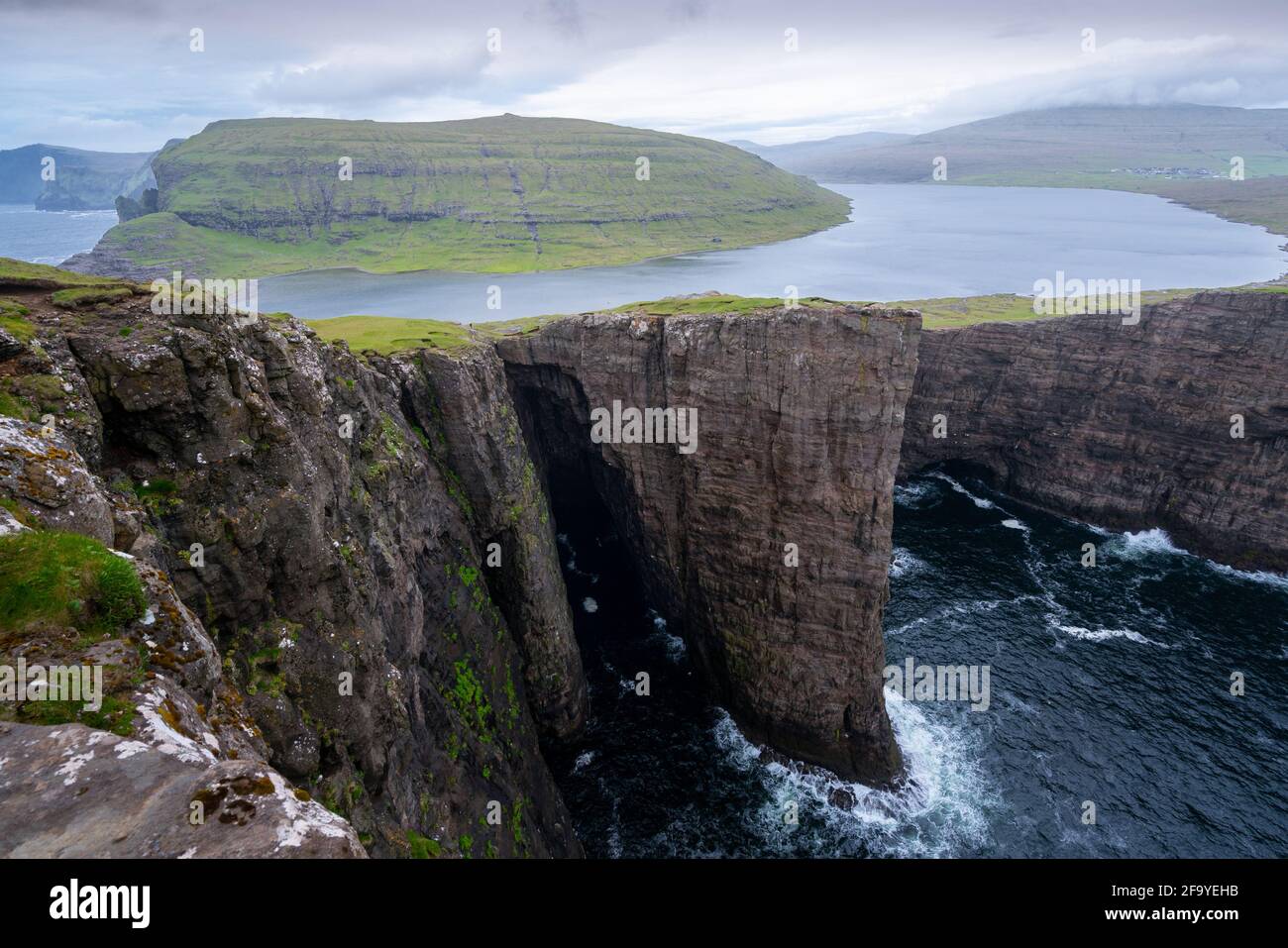 Sorvagsvatn o Leitisvatn, il lago più grande delle Isole Faroe sull'isola di Vagar. Lago su una scogliera alta sopra il mare in una giornata nuvolosa e piovosa. Foto Stock