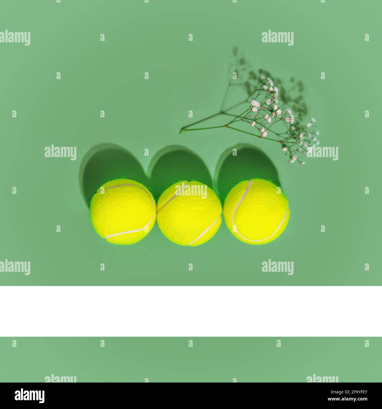 Sport e stile di vita sano. Tennis. Composizione sportiva primaverile con tre palline da tennis gialle e fiori su sfondo verde di campo da tennis. La con Foto Stock