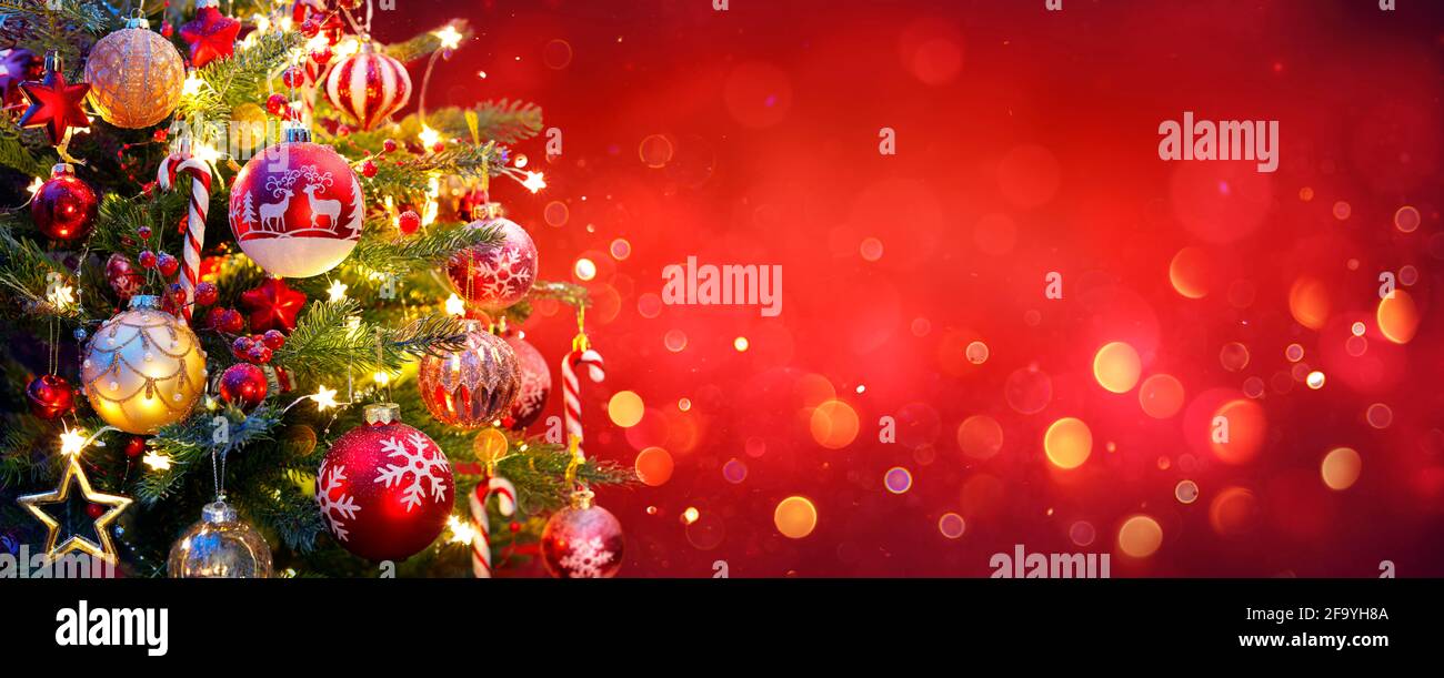 Albero di Natale con luci ornamento e Bokeh in sfondo rosso Foto Stock