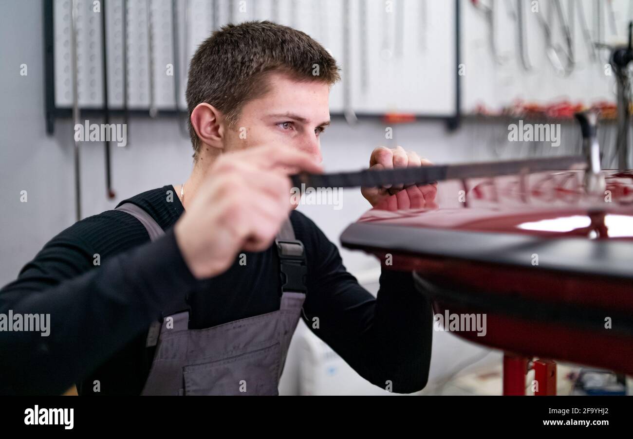 Lavorazione di vernice NO utilizzando la tecnologia di ripristino delle ammaccature da parte di giovani tecnico Foto Stock