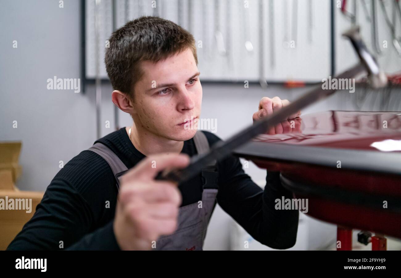 Lavorazione di vernice NO utilizzando la tecnologia di ripristino delle ammaccature da parte di giovani tecnico Foto Stock