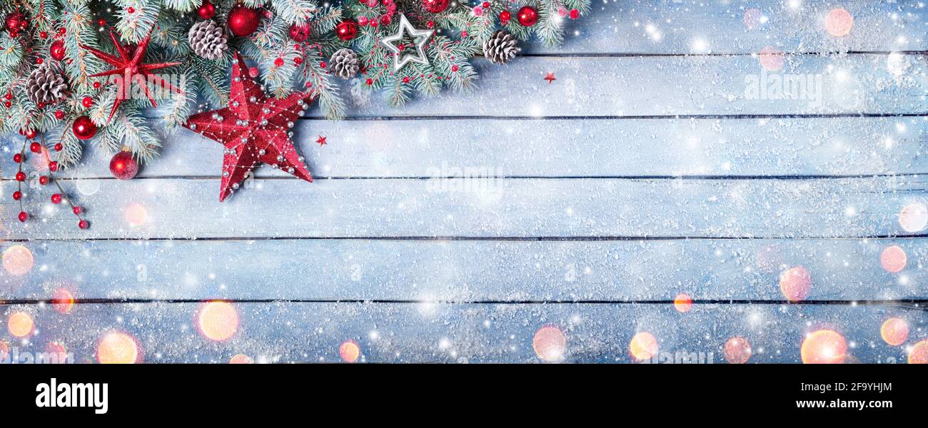 Rami di Abete di Natale su Plank blu di legno con baubles rosso E nevicate Foto Stock