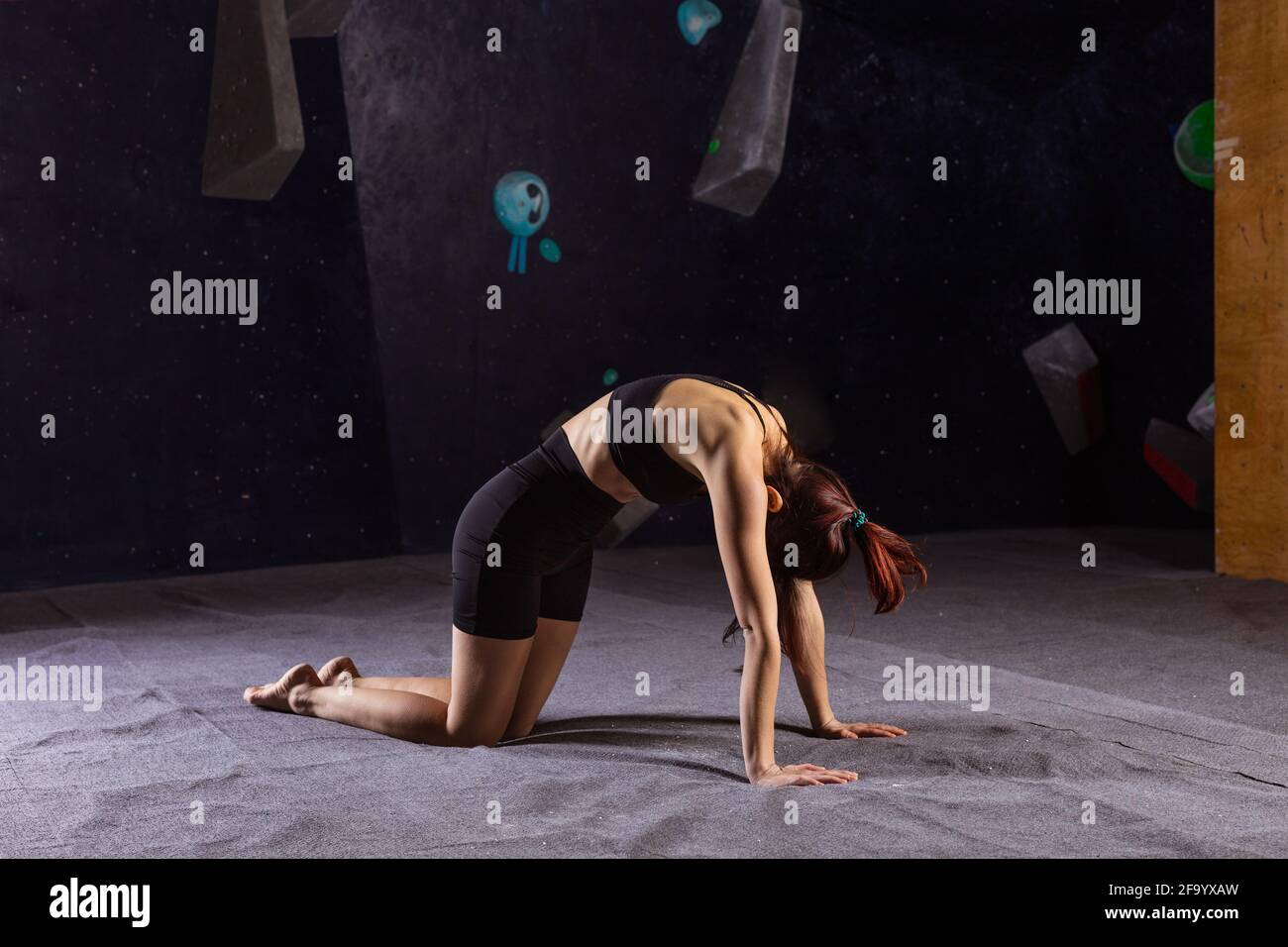 Giovane donna atletica che pratica yoga Gatto Cow posa in indoor palestra per arrampicata Foto Stock