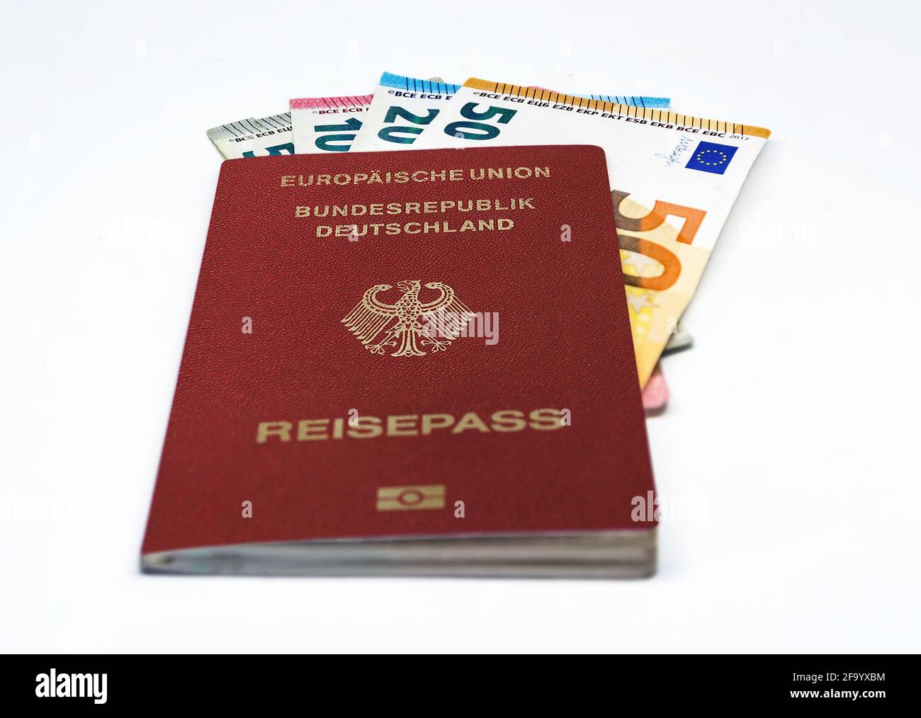 Passaporto di viaggio tedesco con alcune banconote in euro isolate su sfondo bianco. Unione europea e moneta unica. Viaggi e contanti Foto Stock