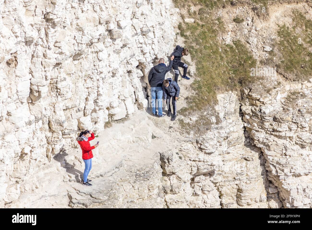 La famiglia si arrampica lungo la pericolosa scogliera costiera a flamborough Head, mentre la mamma si scatta una foto della vista. Preso il 17 aprile 2021 Foto Stock