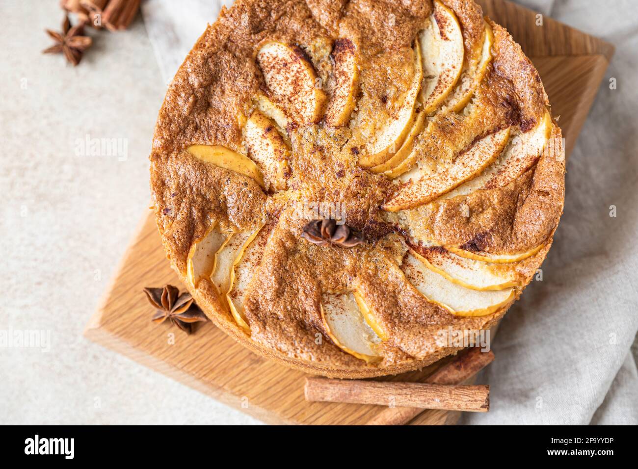 Torta di mele con cannella su tavola di legno, fondo di cemento chiaro. Torta di semola con mela e spezie. Mannik fatto in casa. Messa a fuoco selettiva. Foto Stock
